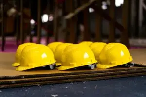 Capacetes de segurança amarelos enfileirados sobre placas de papelão em um canteiro de obras